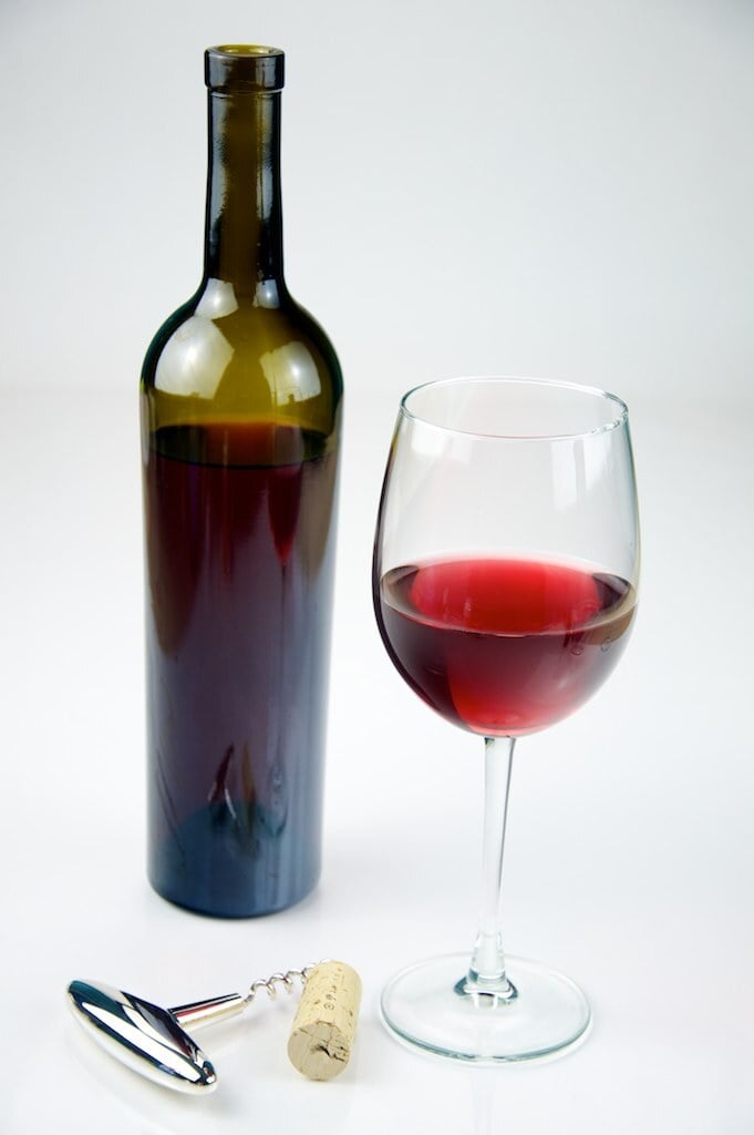 A glass of red wine beside a bottle