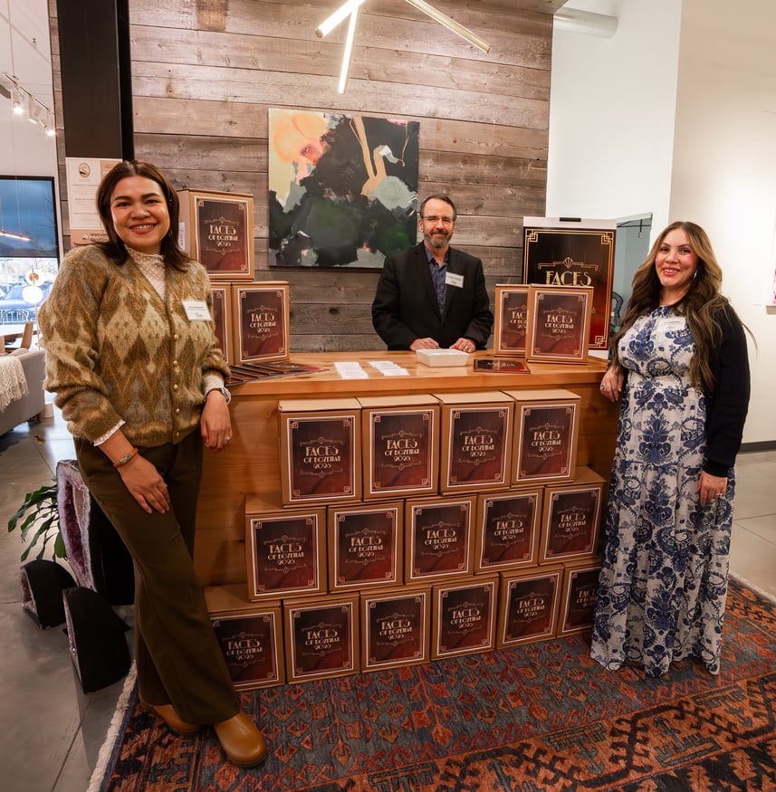 The Faces of Bozeman team behind the counter with stacked Faces boxes at the 2026 launch party