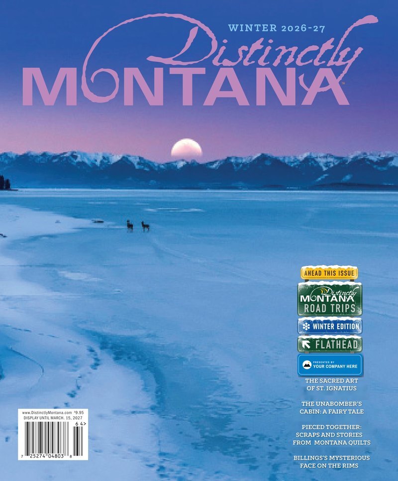 The Winter 2026-27 cover of Distinctly Montana with the Road Trips Winter Edition sign and a blue Presented By sign reading YOUR COMPANY HERE, a mockup